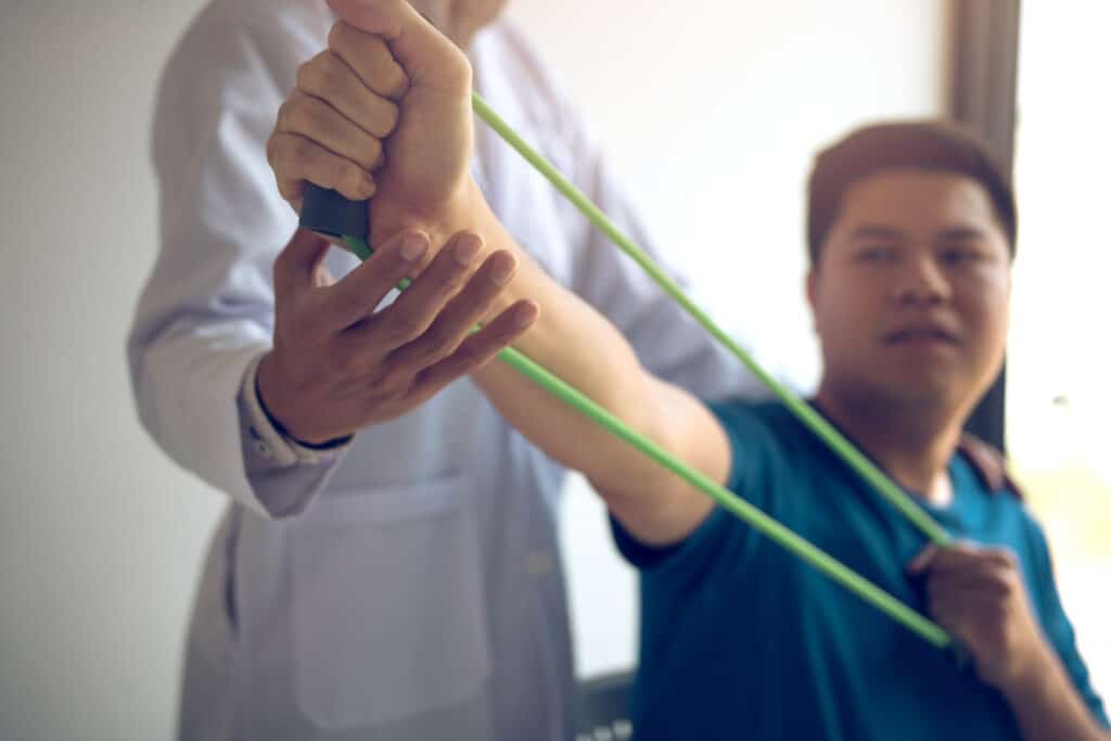 Patient using resistance bands to test his muscle strength after gettin functional wellness treatment.