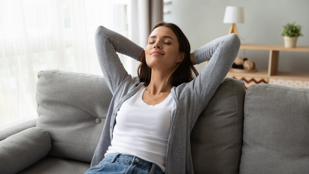 Woman looking very relaxed, laying back on her couch after taking care of her functional wellness.